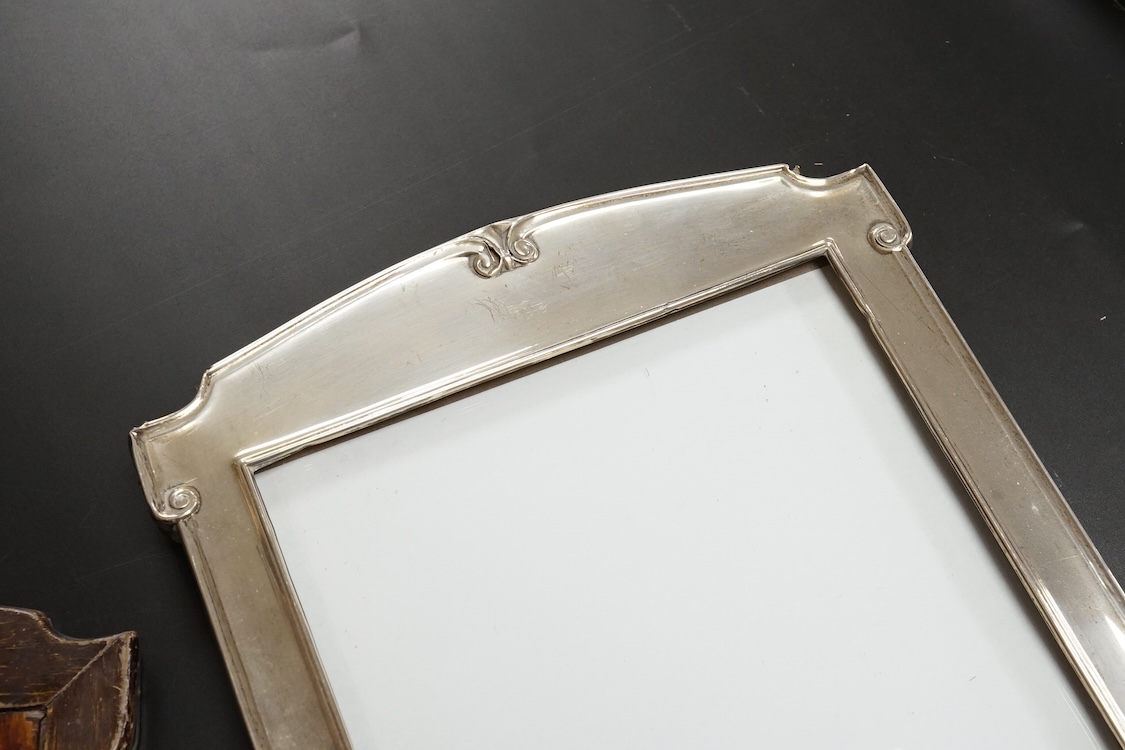 A pair of George V silver mounted shaped rectangular photograph frames, William Neale & Son Ltd, Birmingham, 1922 & 1925, 26.7cm.